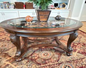 Carved wood glass-top coffee table on Persian rug