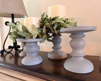 Wood pedestal candle holders with pillar candles and greenery