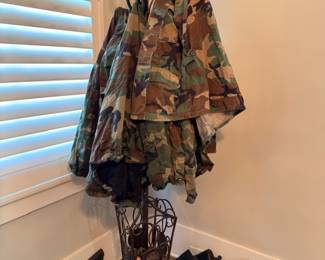 Camo military jackets on iron coat rack with combat boots