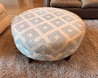 Round upholstered Greek key pattern ottoman