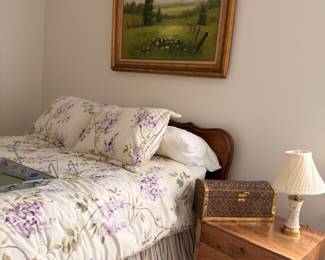 Wood bed with nightstand, lamp, and framed landscape