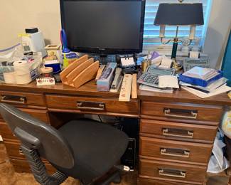 desk with computer monitor and office supplies and rolling office chair