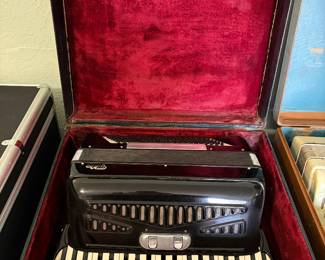 Vintage black Video piano accordion featuring approximately 34 piano keys, dual treble register switches, and approximately 80 bass buttons. Includes the original hard case with red plush interior. Classic mid-century styling with black celluloid finish and chrome accents