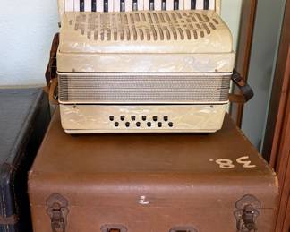Vintage Rivoli ivory pearloid piano accordion featuring approximately 25 piano keys, 12 bass buttons, and multiple treble register switches. Includes the original hard carrying case. Attractive mid-century styling with decorative grille.