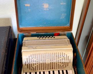 Vintage Rivoli ivory pearloid piano accordion featuring approximately 25 piano keys, 12 bass buttons, and multiple treble register switches. Includes the original hard carrying case. Attractive mid-century styling with decorative grille.