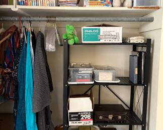 Closet packed with media and collectibles, including DVD collections, vintage VHS tapes, cassette tapes, home-recorded media, a record player in case, Philco DVD player, holiday décor, plush toys, storage organizers, and assorted household items. Great mix of vintage electronics, media, and miscellaneous treasures to explore.