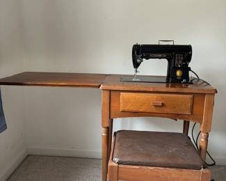 Singer sewing machine in cabinet with stool