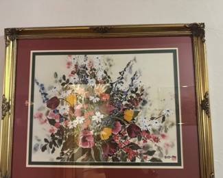 Floral Print in Ornate Gold Frame — This vibrant floral print artwork is showcased in an ornate gold frame with decorative corner embellishments. The print features a colorful bouquet with hues of purple, yellow, red, and white accented by a triple-layered mat in maroon, white, and green tones. The overall framed piece measures approximately 30 inches wide by 27.5 inches tall and extends 1.5 inches deep. It is in good condition with no visible damage to the frame or glass. The print is unsigned or bears a signature that is not clearly identifiable, making it an attractive decorative piece for floral art enthusiasts.