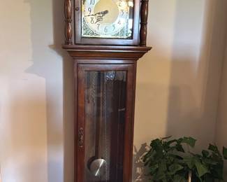 Herschede Tempus Fugit Grandfather — This Herschede Tempus Fugit tall case clock is a classic walnut-finish grandfather clock with ornate dial and arched bonnet. The case features turned columns, glass door revealing the pendulum and chains, and brass-accented clock face marked "Tempus Fugit" and "Herschede". Estimated overall height 88 in, width 20 in and depth 12 in; heavy solid-case construction suitable for a living room focal point. Clock appears in good condition cosmetically with minor surface wear consistent with normal use; working condition unknown and sold as-is. A traditional American-made Herschede piece, desirable to collectors and decorators for its quality movement and timeless styling.
