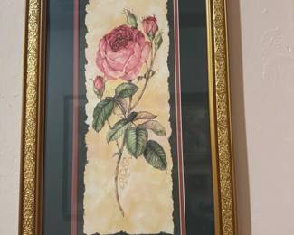 Framed Pink Rose Botanical Print — This elegant framed botanical print features a detailed pink rose illustration with surrounding rosebuds and textured background. The artwork is set within an ornate gold frame with floral carvings and a dark green and pink double mat that complements the colors of the rose. The frame measures approximately 24 inches in height and 14.5 inches in width, making it a striking vertical piece for wall decor. The print and frame are in good condition with no visible damage. This classic floral artwork adds a vintage charm to any living space or gallery wall.