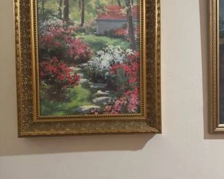 Floral Garden Landscape Oil Painting — This vibrant oil painting captures a serene garden landscape with colorful blooming flowers and a quaint building in the background. The artwork is surrounded by an ornate, gold-toned frame that enhances its classic appeal. The painting measures approximately 24 inches in height and 19 inches in width, making it suitable for a variety of wall spaces. It is in good condition with no visible damage to the frame or canvas. This peaceful garden scene will add a touch of tranquility and classic charm to any home decor.