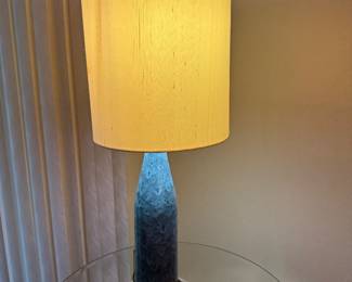 Contemporary Blue Art Glass Table Lamp with Linen Shade Description: Add a touch of modern elegance to your living room, bedroom, or Florida room with this beautiful contemporary table lamp. Featuring a textured blue ombré art glass base and a neutral linen drum shade, it provides a warm, inviting glow that complements coastal, transitional, and modern décor.