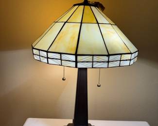 Add timeless elegance to your home with this beautiful Tiffany-style table lamp featuring a warm amber and ivory art glass shade with classic geometric detailing. The substantial bronze-finished base and dual pull-chain operation combine beauty with everyday functionality.