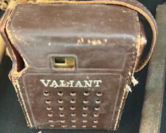 Transistor radio — Small brown leather carrying case marked "VALIANT" on the front, shown with perforated front panel and a snap/strap closure. Construction appears stitched leather with some surface wear, scuffs and light separation at seams consistent with age and use. Useful as a display piece or to hold a compact device or accessory; no internal contents are shown and functionality is unknown. Measures small and portable — see dimensions below.