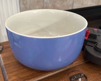 Blue Ceramic Mixing Bowl — Large blue-glazed ceramic mixing bowl with a glossy white interior. Simple rounded form with an unmarked foot ring; shows light surface wear and some interior scuffing consistent with use but no obvious chips or cracks. Sturdy, heavy feel suitable for serving or kitchen prep; color is a soft periwinkle-blue on the exterior with a white glazed interior. Measures roughly as listed and sold as a single decorative/functional bowl.