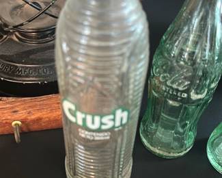 Crush Embossed Soda Bottle — Clear glass Crush soda bottle with embossed ribbed body and printed green "Crush" logo on the front. Solid blown-mold bottle likely mid-20th century; display piece with light surface wear, no obvious cracks or chips visible in photos. Good decorative collectible for soda memorabilia collectors; measures small and easy to display on a shelf or in a cabinet.