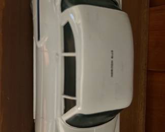 Horizon Blue Toy Car Bank — White tin windup toy car with metal bumpers and simple painted windows; key-wind mechanism visible on the underside. The piece shows light surface wear and small paint chips consistent with use but retains original wheels and chrome-plated bumpers. A utilitarian mid-century style tin toy suitable for display or a small collection; mechanism was not tested and seller notes do not state working condition. Measures approximately 9 inches long and is a compact decorative toy car.