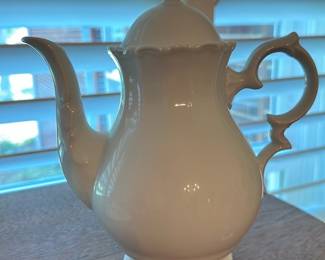 Crown Mark Porcelain Coffee Pot — White porcelain coffee/teapot with an ornate scrolled handle and finial, marked with a green crown-style maker's mark on the base. The classic baluster body and molded foot rim suggest traditional European-style tableware; the piece appears intact with glossy glaze and no visible chips or cracks in photos. Marking is shown in green on the underside but not fully legible; sold as a decorative or serving piece for dining-room use. Measures roughly 10–11 inches tall and is a lightweight porcelain suitable for display or occasional service.