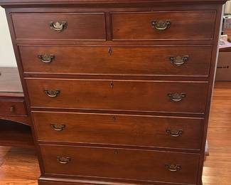 Craftique Cherry Tall Dresser — This authentic reproduction Craftique tall dresser in cherry finish offers classic traditional styling and solid wood construction. It features two small top drawers over four full-width drawers with brass bail pulls, dovetail construction, and decorative bracket feet. Measuring approximately 48 inches high, 38 inches wide and 18 inches deep, it provides generous bedroom storage while maintaining a compact footprint. The dresser is in good condition with light surface scratches and minor wear consistent with normal use; hardware and drawer function are intact.