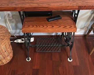 Singer Treadle Sewing Machine Table — Solid oak tabletop mounted on a cast-iron Singer-style treadle base, offered as a decorative console or repurposed table. The wood top and center shelf show a warm grain with light surface wear and the original cast-iron treadle, pedals and connecting rod are intact; metal has surface patina consistent with age. Sturdy construction makes it suitable for hallway or entry use; measures show typical compact sewing-table proportions. Condition is good with cosmetic wear and no obvious structural damage visible.