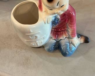 Royal Coplay Figure Planter — Glazed ceramic figural planter marked "Royal Coplay" on the base. The piece depicts a seated child in a red jacket and blue pants leaning on a small white planter with embossed detailing; gloss glaze and subtle crazing visible. Good collectible condition with expected surface wear, light staining at the base rim, and no obvious chips or large cracks in photos. A small, decorative shelf or desk planter that would suit collectors of mid-century ceramics.