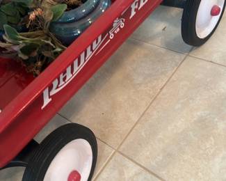 Radio Flyer Red Wagon — Classic Radio Flyer red metal wagon used here as a planter but complete with original red paint, white wheel centers and black rubber tires. The recognizable "RADIO FLYER" logo is visible on the side; body shows light surface scratches and minor scuffs consistent with gentle outdoor or decorative use. Solid wheels and frame appear functional for play or display; a great piece for kids or repurposing as indoor/outdoor decor. Measures compactly for easy transport and light gardening projects.