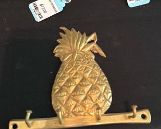 Brass Pineapple Wall Key Rack — Brass pineapple wall key rack with three hooks and two mounting holes. Solid cast brass look with a stylized pineapple motif—good decorative piece for entry or kitchen storage. Shows light surface wear and patina consistent with age; hooks appear intact and straight. Compact, easy to mount and useful for keys or small hanging items.