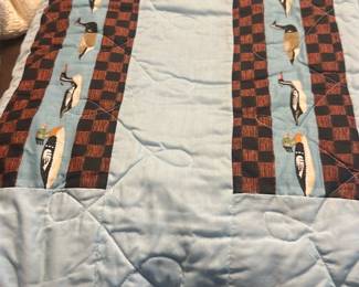Light Blue Duck Appliqué Quilt — Light blue quilt with two vertical appliqué panels featuring stylized ducks over a checkerboard strip. Soft cotton top with quilted stitching and plain blue binding; shows light overall wear and a few small spots/stains visible in photos. A nice decorative throw or baby/child quilt measuring a modest size and easy to launder; condition is good for use with noted spotting.