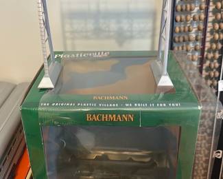 Bachmann Plasticville Signal Gantry — Bachmann Plasticville O-scale signal gantry in silver finish, shown with its original green Plasticville box. The piece is a detailed model railroad signal bridge with three hanging signals and laddered supports; good display piece for Plasticville or O-scale layouts. Box shows wear and a torn display window as photographed; the gantry itself appears complete with some light surface wear from handling. Compact model suitable for shelf display or layout use; see photos for exact condition and included parts.