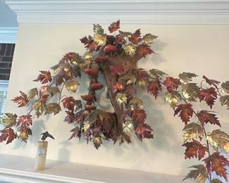 Metal Maple Leaf Wall Sculpture — Decorative metal wall sculpture shaped like a hanging maple branch with many red, gold and copper-tone leaves. The piece appears to be a lightweight metal fabrication with painted/leafed finish and an integrated wood-look central support; good for mantel or entry display. Shows light surface wear and small paint loss consistent with age and indoor use but no major damage visible in photos. Overall substantial visual impact at approx. mantel-to-ceiling height — ideal as seasonal or year-round accent.