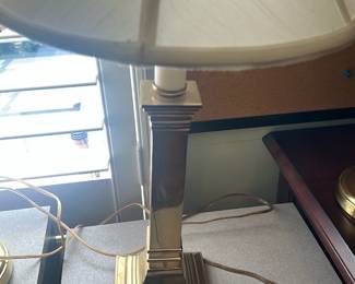 Brass Column Table Lamp — Polished brass column table lamp with stepped square base and a white fabric bell shade. Clean, classic design suits desk or bedside use; the finish shows typical light surface wear and small scuffs consistent with normal use but no major dents. Shade is intact with minor age discoloration visible in photos. Overall a solid, functional decorative lamp approximately medium size.