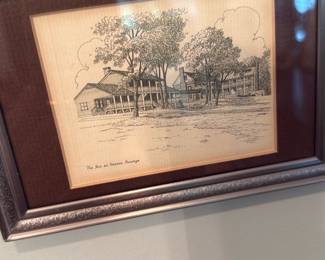 The Inn at Navarro Passage Print — Framed black-and-white ink drawing titled "The Inn at Navarro Passage" shown here in a silver decorative frame with brown mat. The image depicts a classic inn building with trees and porches in a fine pen-and-ink style; signature or artist name is not legible in the photos. Frame shows light surface wear and the print has mild age toning around margins. Overall good condition and ready to hang as shown.