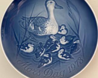 B&G Mother's Day 1973 Plate — Royal Copenhagen / Bing & Grondahl (B&G) porcelain decorative plate commemorating "Mother's Day 1973" in classic blue-and-white cameo style. The plate features a mother duck and ducklings motif in blue underglaze with "Mors Dag 1973" script and factory backstamp reading B&G Copenhagen Porcelain, Made in Denmark, model 8000/9373. Approximately the size of a small wall plate, it includes a wired hanger on the back and shows light age-appropriate surface wear but no visible cracks or chips. A collectible commemorative piece suitable for display in a living room or china cabinet; produced in Denmark and marked on the reverse.