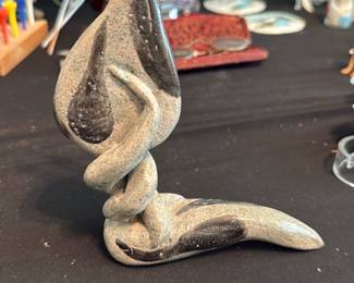 Abstract Stoneware Pottery Sculpture — Handmade abstract stoneware sculpture with a twisted, flowing form and matte speckled gray glaze accented by darker brushstrokes. The organic, modern shape suggests a mid-century inspired studio piece suitable for a shelf or mantel; photos show no obvious chips or cracks but there is light surface wear consistent with age and handling. Kiln-fired ceramic construction with a stable flat base, approximately small tabletop size. Sold as a single decorative pottery sculpture.