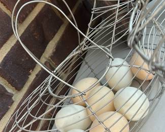Wire Chicken Egg Basket — A rustic wire chicken-shaped egg basket suitable for kitchen or sun room display. Constructed from silver-tone wire formed into a chicken silhouette with an integrated handle and open-grid body; shown holding several eggs. Light surface wear and some patina consistent with age and use but structurally sound. Measures compactly and is easy to hang or set on a counter as functional farmhouse decor.