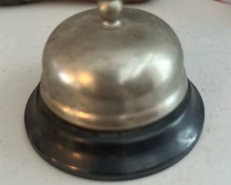 Desk Service Bell Metal — Small metal desk/service bell with a silver-tone dome and black base. Classic push-top design used for reception desks or counters; photos show light surface wear and patina consistent with age and use but no obvious dents or missing parts. Solid, simple construction makes it useful as a functional antique-style counter bell or decorative accent. Measures small and is easy to display on a desk, shelf or in a collection of service items.