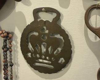 Brass Crown Trivet — Heavy brass trivet cut in a decorative crown motif with scalloped outer edge and hand-cut openwork. Solid, mid-weight piece that appears to have surface oxidation and patina consistent with age; no breaks or repairs visible in photos. Works well as a functional pot trivet or wall decor accent; measures small to medium and is cast from a single sheet of brass/bronze. Good overall condition with expected surface wear and darkening from use.