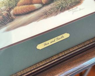 John Shaw Fox and Turtle 1st Ed — Framed signed limited-edition print titled "Fox and Turtle" by John Shaw, numbered 615 of 950 and dated Aug. 2, 2001 per the included Certificate of Authenticity. Image shows a resting red fox in grassy detail with the artist's printed credit and signature visible on the margin; frame has a green double mat and small brass title plaque. Good overall condition with normal glass reflection and light surface wear to the wooden frame; print and signature appear intact and well presented. Ready to hang as shown; frame preserves the print and COA is included.