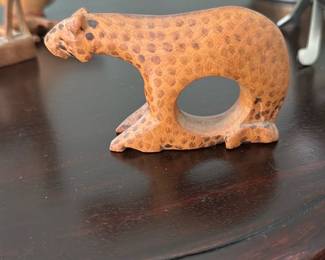 Handcarved Wood Leopard Figurine — Small handcarved wooden leopard with a pierced center and painted spotted surface. The piece appears handcrafted with simple folk-style carving and hand-applied brown spotting; there is light surface wear and some paint loss consistent with age. Good decorative accent for a shelf or desk; compact and lightweight. No maker's marks visible in photos.