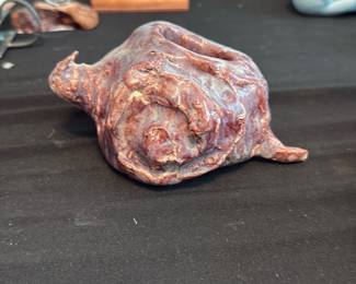 Snail Pottery — Handmade ceramic sculpture shaped like a spiral sea shell or conch, with a textured, earthy glaze in brown and reddish tones. The piece appears wheel-formed or hand-built with visible tool marks and a rustic finish, suitable for shelf or tabletop display in a coastal or eclectic decor. No maker's marks or labels are visible in the photos; condition is good with expected handmade surface irregularities and no obvious chips or breaks. Compact decorative object measuring approximately the dimensions listed below.