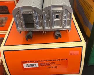 Lionel Southern Streamliner 2-Pack — Lionel Southern Streamliner passenger car 2-pack shown in original orange Lionel box. Two silver Southern-branded streamlined passenger cars with detailed roofs and end doors; boxed but cars appear unpainted or primer-gray (see photos). Good collectible condition with light shelf wear to box and no obvious broken parts on cars; couplers intact. Ideal for Lionel O gauge layouts or a collector replacing missing passenger cars.
