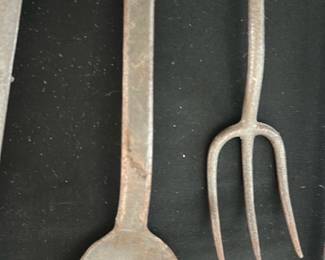 Kitchen Serving Spoon — A matched pair of long iron serving implements — a three-tine fork and a deep spoon — with hand-forged appearance and honest surface oxidation consistent with age. Simple square-section handles and utilitarian form suggest 19th–early 20th-century farmhouse or hearth use; both pieces show surface rust and pitting but remain solid. Good candidate for decorative display, restoration, or use after cleaning and stabilization. Measurements are approximate — see dimensions for overall size.