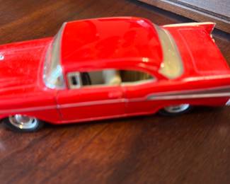 1957 Chevrolet Bel Air Toy Car — Red 1957 Chevrolet Bel Air die-cast style toy car with chrome trim details and molded interior. Marked on the underside "1957 Chevrolet Bel Air used under license" and "QINGYI/MADE IN CHINA 0216075", with realistic tires and painted silver side accents. Compact tabletop model suitable for display or play; estimated small size and lightweight for easy shelving or children's use. Overall good condition with minor surface wear and light paint scuffs visible in photos.