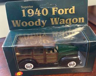 1940 Ford Woody Wagon Model — Die-cast model of a 1940 Ford Woody Wagon in original retail box; the packaging is labeled "Superior 1940 Ford Woody Wagon". The model features wood-panel styling on the sides with a green and brown painted finish and whitewall-style wheels. Compact boxed collectible suitable for display on a shelf or in a curio cabinet; box measures approximately 6 in wide (see dimensions). The item appears in good condition inside original box with minor shelf wear to the cardboard display packaging.