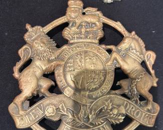 Brass Royal Coat of Arms Plaque — Heavy brass plaque showing the British royal coat of arms with crowned lion, unicorn, central quartered shield and banner reading "DIEU ET MON DROIT." Solid-cast with aged patina and surface wear consistent with age; some verdigris and small dings visible at edges. Decorative wall or furniture mount accent likely used as a crest or military/regimental badge; substantial weight for its size. Good overall condition for display with honest surface wear; no major cracks or repairs noted.