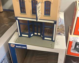 Built-Ups Silver Dollar Cafe — Built-Ups Silver Dollar Cafe plastic model storefront from the Built-Ups line, shown with its original box and assembled facade. The kit recreates a two-story brick cafe with blue-trim storefront, sidewalk base and hanging sign; box art and back panel text are intact. Good collectible condition with light shelf wear to box and no obvious breakage to the assembled building visible in photos. Measures a compact footprint suitable for model railroad or diorama display.