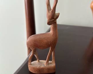Hand Carved Wood Antelope Figurine — Small hand-carved wooden antelope figurine with stylized long horns and a rectangular base. Simple mid-century folk-carving style with a warm natural wood patina and light surface wear consistent with age; no visible chips or breaks in photos. A decorative accent suitable for a bookshelf, desk, or mantel; lightweight and easy to display. Measurements are estimated from photos.