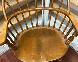 Windsor Style Wooden Armchair — Solid wooden Windsor-style armchair with swept back spindles and turned legs and arm supports. The chair shows honest wear to the seat surface and finish consistent with age and use but remains structurally sound with no broken spindles visible. A classic farmhouse or country-style accent chair that would work in a study, entry or dining nook; measures roughly as listed. Good usable condition with surface wear and light scuffs.