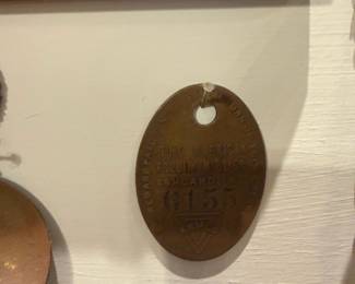 The American Rolling Mill Co. Tag — Brass identification tag stamped "THE AMERICAN ROLLING MILL CO. ASHLAND KY" with number "0155" and triangular mark; oval tag has a punched hole at top and shows age-appropriate patina. Solid, utilitarian mill tag likely used for factory inventory or worker identification and suitable for industrial collections or display. Surface wear and oxidation consistent with age; no major bends or breaks visible from photos. Measures small and lightweight—see dimensions and weight below.