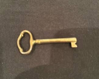 Brass Skeleton Key — Solid brass skeleton key with an octagonal/rounded bow and simple barrel shaft; photographed from several angles. Unmarked and appears to be a decorative or older utility key rather than a modern lock key. Shows light surface wear and patina consistent with age but no obvious bends or breaks. Handy as a replacement key for an older cabinet or as decorative hardware or collectible.